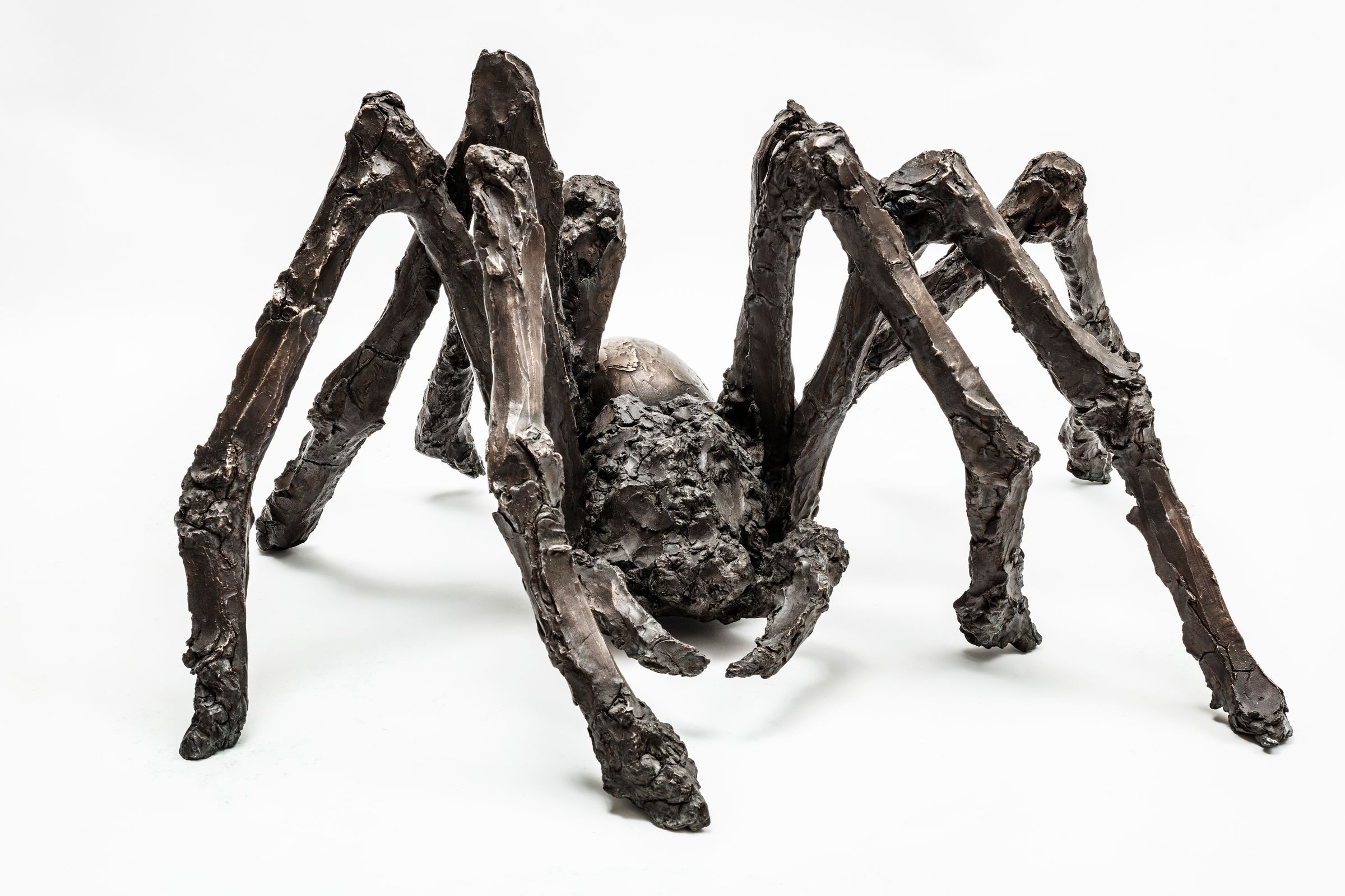Bronzeskulptur af en edderkop med menneskelignende ansigt og otte grove ben i ekspressiv stil. Spider af Maria Rubinke, 2019. Højde 50 cm. Edition 5.